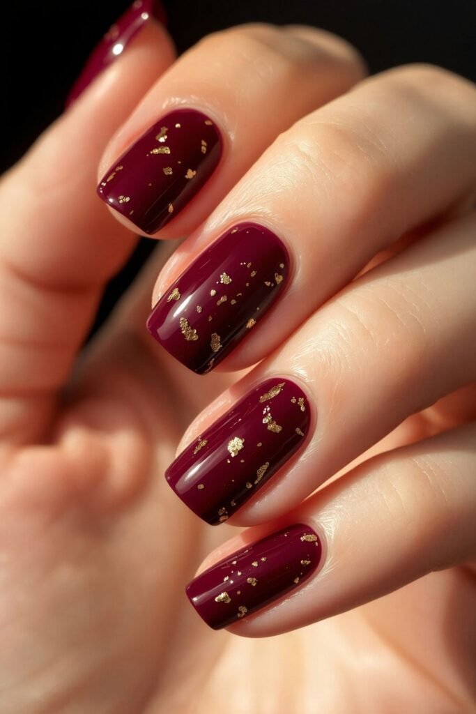Deep burgundy fall nails with scattered gold leaf flecks